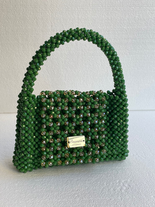 Sac Bassmera Emeraudea artisanal tissé en cristal vert émeraude avec accents champagne, vue de trois quarts avant avec plaque dorée.
