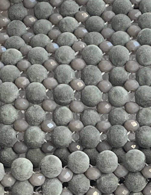 Gros plan du sac Bassmera Griselle montrant les perles en suède gris mat et les cristaux de verre scintillants.