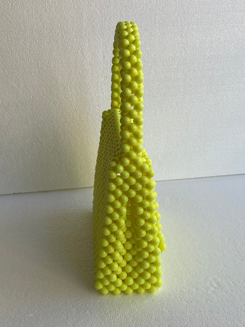 Sac Bassmera Citrina jaune fluo en perles, vue de profil étroite montrant la profondeur rectangulaire et la double poignée arquée.