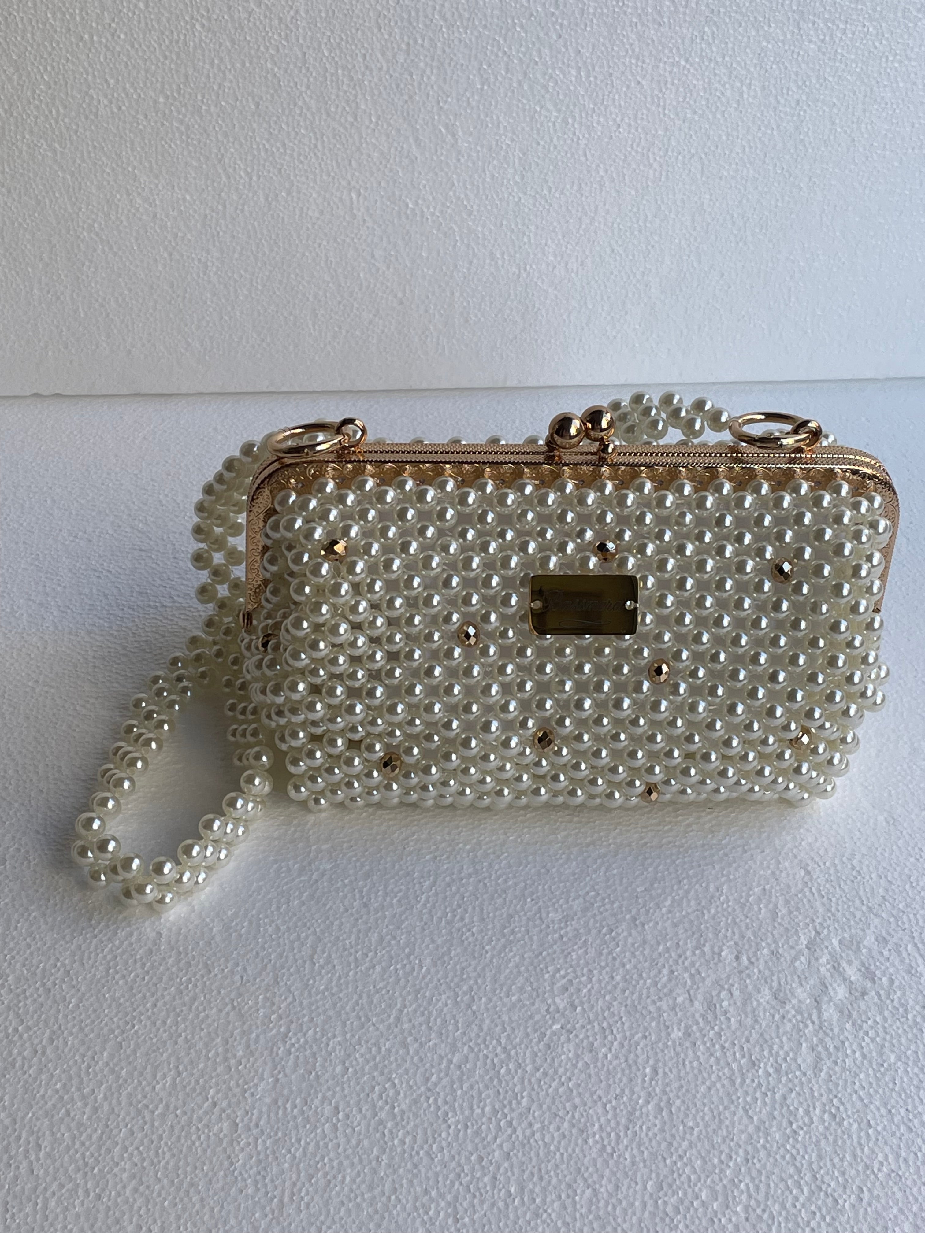 Sac de soirée Bassmera Lunea en perles nacrées blanc cassé, vue de face avec cristaux, cadre doré, plaque Bassmera et poignée perlée.