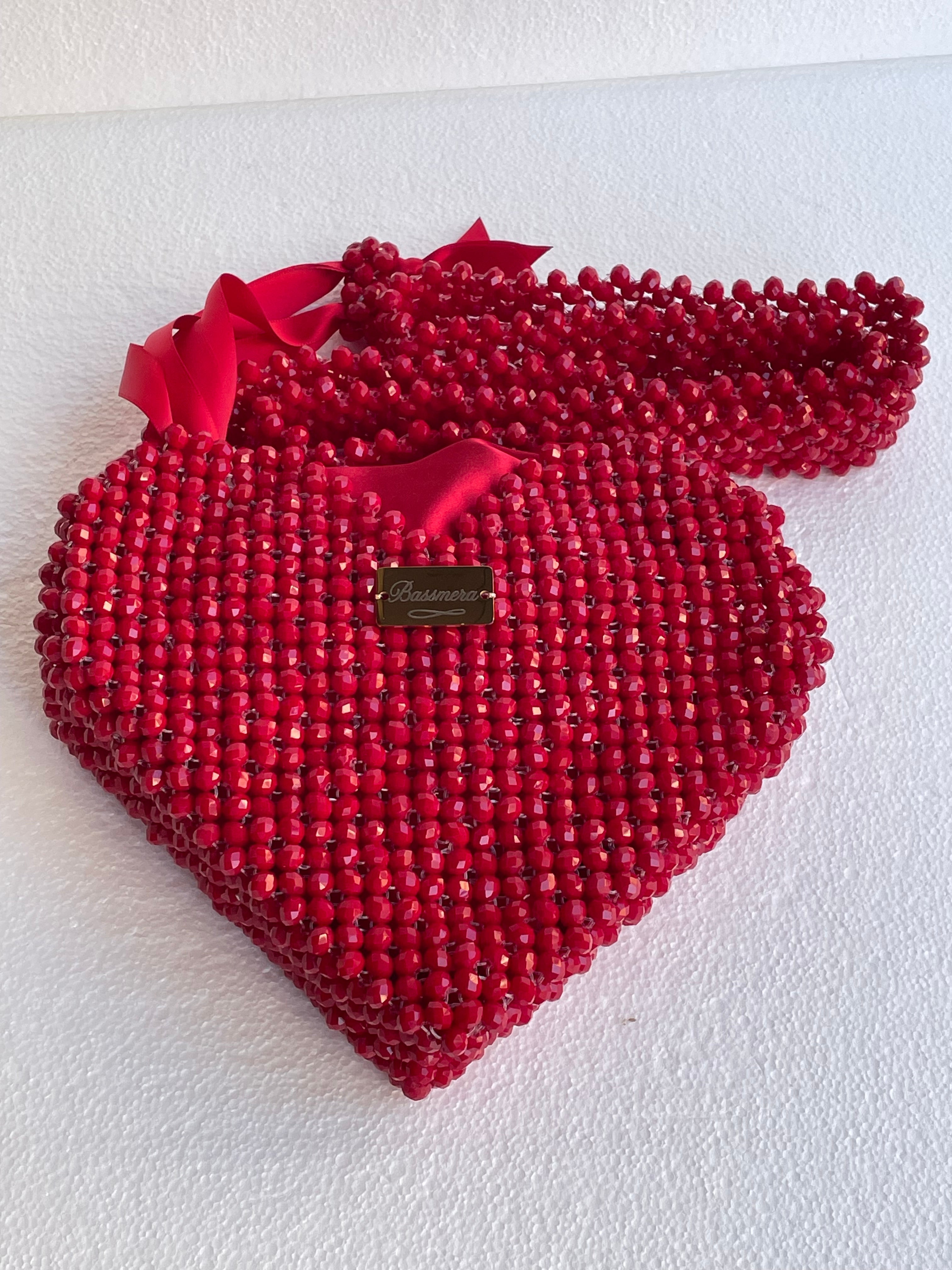 حقيبة قلب Bassmera Valentina Crimson، من الكريستال الأحمر، على خلفية بيضاء، مع جراب ساتان أحمر، ولوحة Bassmera ذهبية