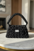 Black Bassmera beaded bag magnified on marble table